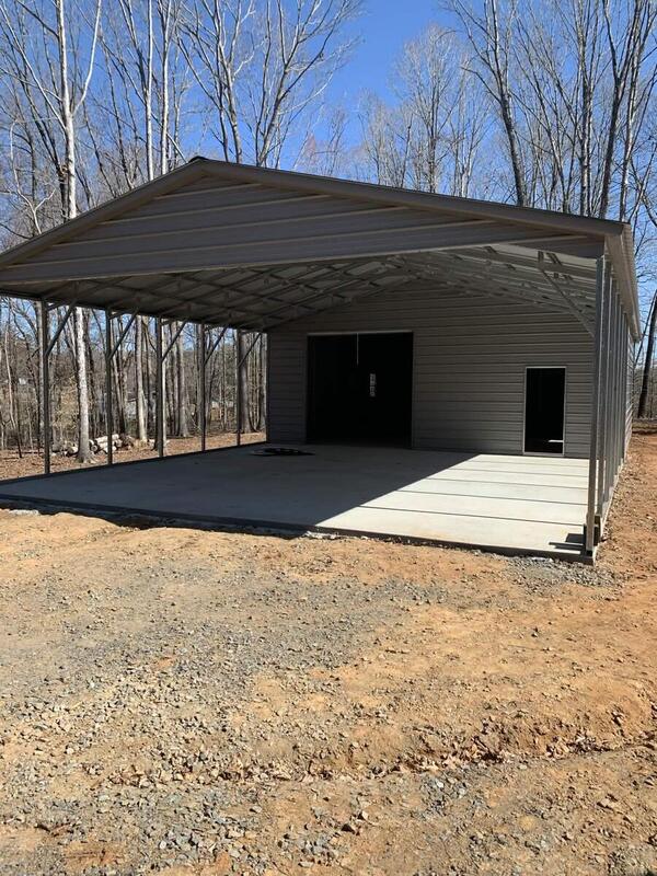 Front view of an open-sided metal carport on a concrete slab with an enclosed storage room at the back