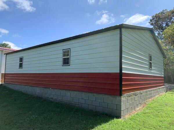 White metal garage with red lower panels and three windows, set on a block foundation