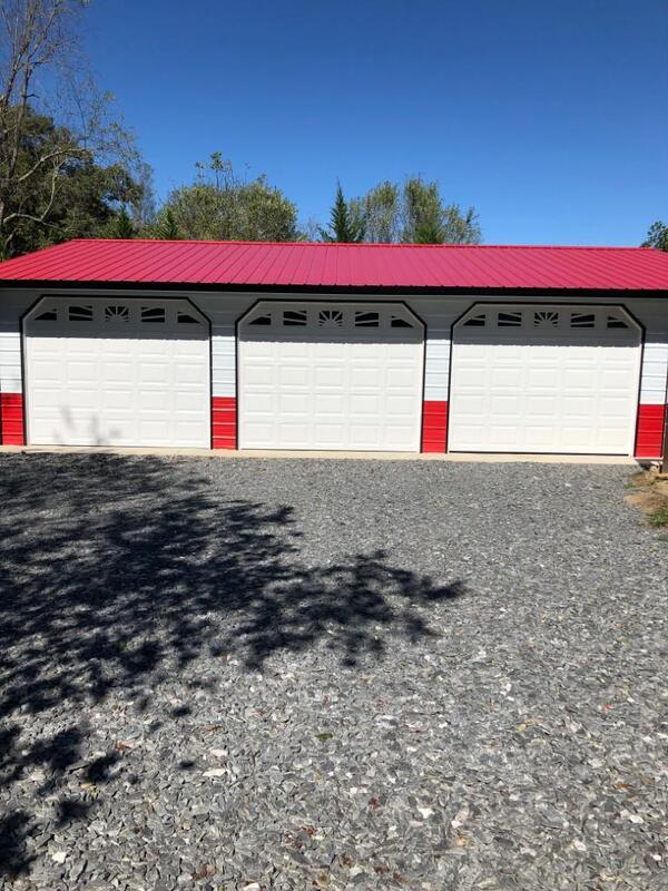 Front of a three-car metal garage with a red roof and white raised-panel garage doors
