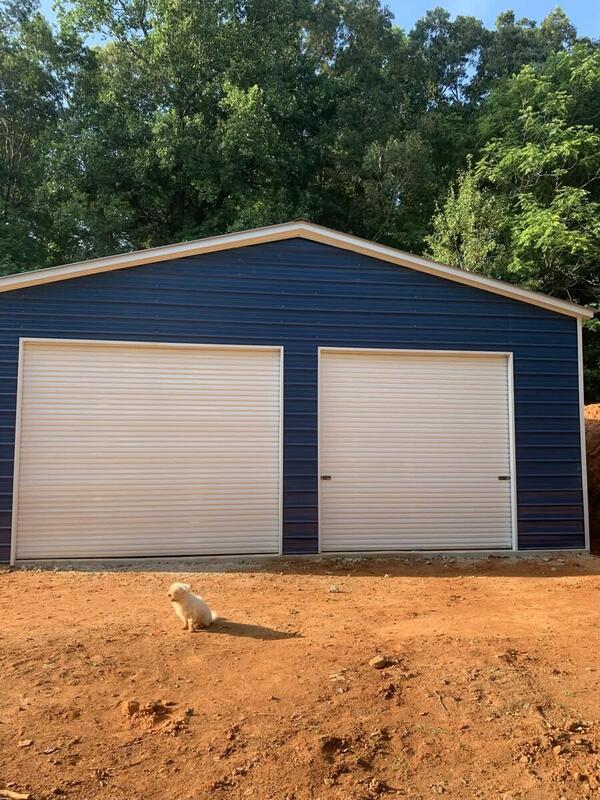 Front of a blue metal garage with two white roll-up doors