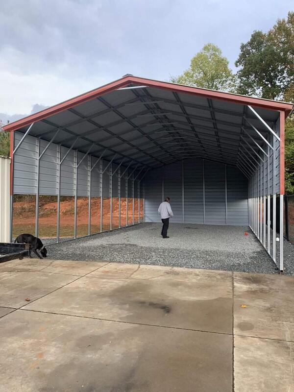 Tall metal cover with red trim, partly enclosed sides, and a closed back wall, over gravel