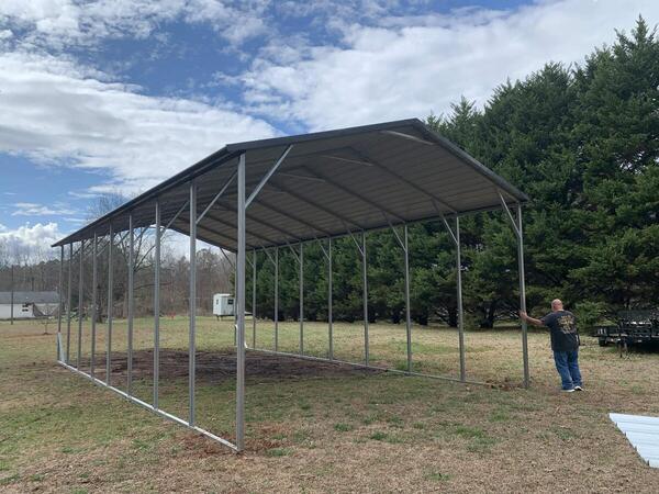 Tall open-sided metal cover on a grassy lot